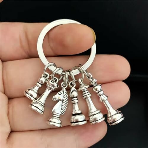 Hand holding a keychain with silver chess pieces.