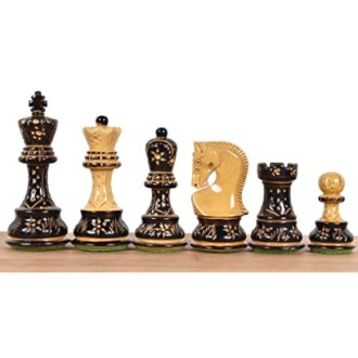 Set of ornate black and gold chess pieces on a wooden board.